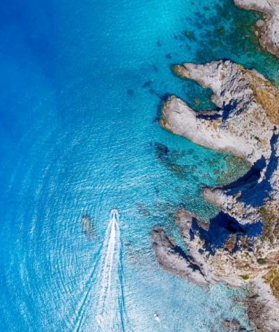 Vista aerea di un mare cristallino con scogliere e una barca.